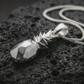 Load image into Gallery viewer, Polished silver origami pineapple pendant necklace displayed on black volcanic rock, shown in a refined macro product shot with faceted geometric body and sharp folded leaf crown detail.
