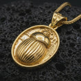 Load image into Gallery viewer, Gold plated Egyptian scarab pendant necklace presented on porous volcanic rock, highlighting the ancient protective amulet design in a luxurious close-up jewelry image.

