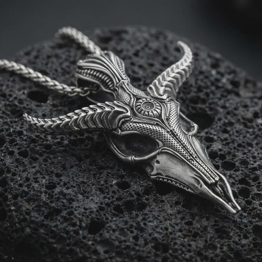 Sterling silver Baphomet skull pendant necklace with an oxidized finish resting on textured volcanic rock, captured in a close-up premium studio composition.