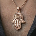 Load image into Gallery viewer, Rose gold plated Hamsa hand pendant necklace worn on the neck, presented in a close-up lifestyle shot with a refined symbolic aesthetic.
