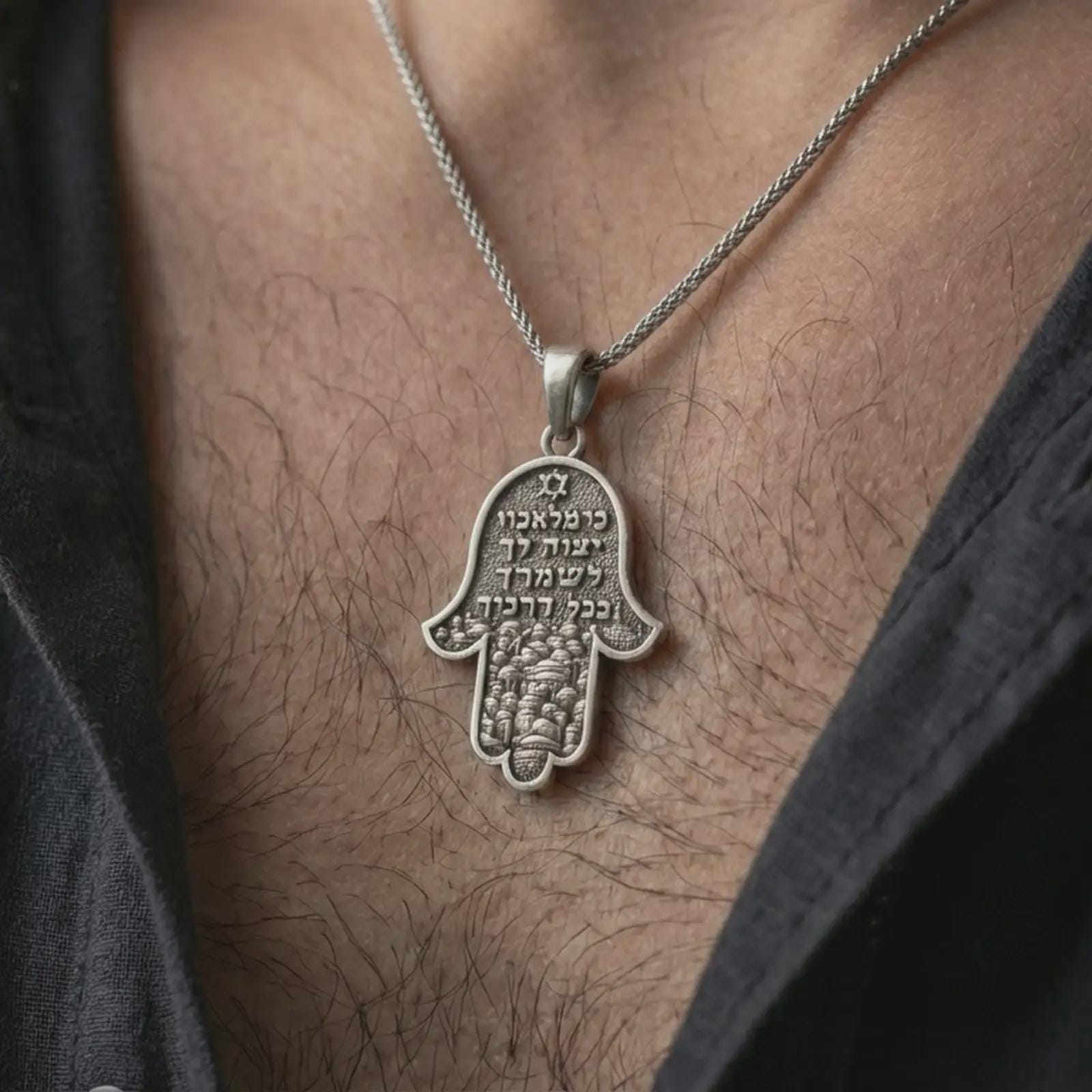 Oxidized Jerusalem Hamsa hand pendant necklace worn on the neck, styled in a dark lifestyle portrait with an open shirt and meaningful presentation.