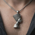 Load image into Gallery viewer, Oxidized Nefertiti pendant necklace worn on the neck, styled in a dark lifestyle portrait with an open shirt and elegant presentation.
