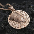 Load image into Gallery viewer, Rose gold plated Nefertiti medallion pendant necklace on dark volcanic rock, photographed in a detailed premium studio macro view.
