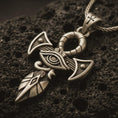Load image into Gallery viewer, Bronze Eye of Horus ankh pendant necklace with an oxidized finish resting on textured volcanic rock, captured in a close-up premium studio composition.
