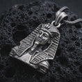 Load image into Gallery viewer, Sterling silver Tutankhamun pendant necklace with an oxidized finish resting on textured volcanic rock, captured in a close-up premium studio composition.
