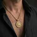 Load image into Gallery viewer, Gold plated Knights Templar seal pendant necklace worn on the neck, captured on a human model in a premium dark-toned lifestyle frame.

