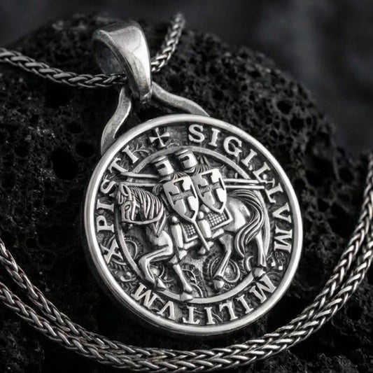 Sterling silver Knights Templar seal pendant necklace with an oxidized finish resting on textured volcanic rock, captured in a close-up premium studio composition.