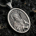 Load image into Gallery viewer, Sterling silver Saint Patrick pendant necklace with an oxidized finish resting on textured volcanic rock, captured in a close-up premium studio composition.
