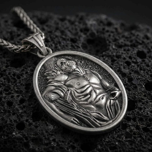 Sterling silver Saint Sebastian pendant necklace with an oxidized finish resting on textured volcanic rock, captured in a close-up premium studio composition.