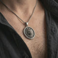 Load image into Gallery viewer, Oxidized snarling wolf pendant necklace worn on the neck, styled in a dark lifestyle portrait with an open shirt and bold masculine presentation.
