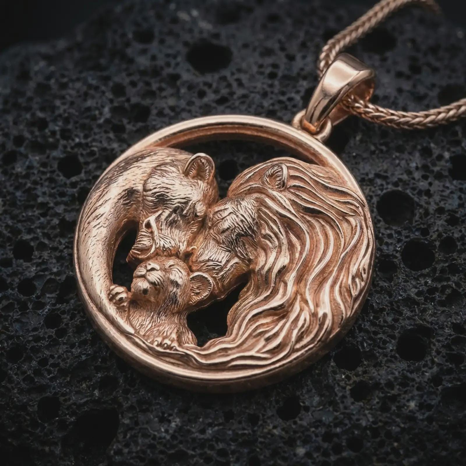 Rose gold plated lion and bear family pendant necklace on dark volcanic rock, photographed in a detailed premium studio macro view.