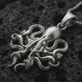 Load image into Gallery viewer, Sterling silver octopus pendant necklace with an oxidized finish resting on textured volcanic rock, captured in a close-up premium studio composition.
