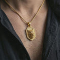 Load image into Gallery viewer, Gold plated ferocious wolf shield pendant necklace worn on the neck, captured on a human model in a premium dark-toned lifestyle frame.
