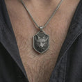 Load image into Gallery viewer, Oxidized fox shield pendant necklace worn on the neck, styled in a dark lifestyle portrait with an open shirt and elegant presentation.

