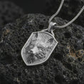 Load image into Gallery viewer, Polished silver fox shield pendant necklace displayed on black volcanic rock, shown in a refined macro product shot with alert fox face relief, flowing fur detail, and angular shield frame.

