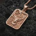 Load image into Gallery viewer, Rose gold plated stag forest pendant necklace on dark volcanic rock, photographed in a detailed premium studio macro view.
