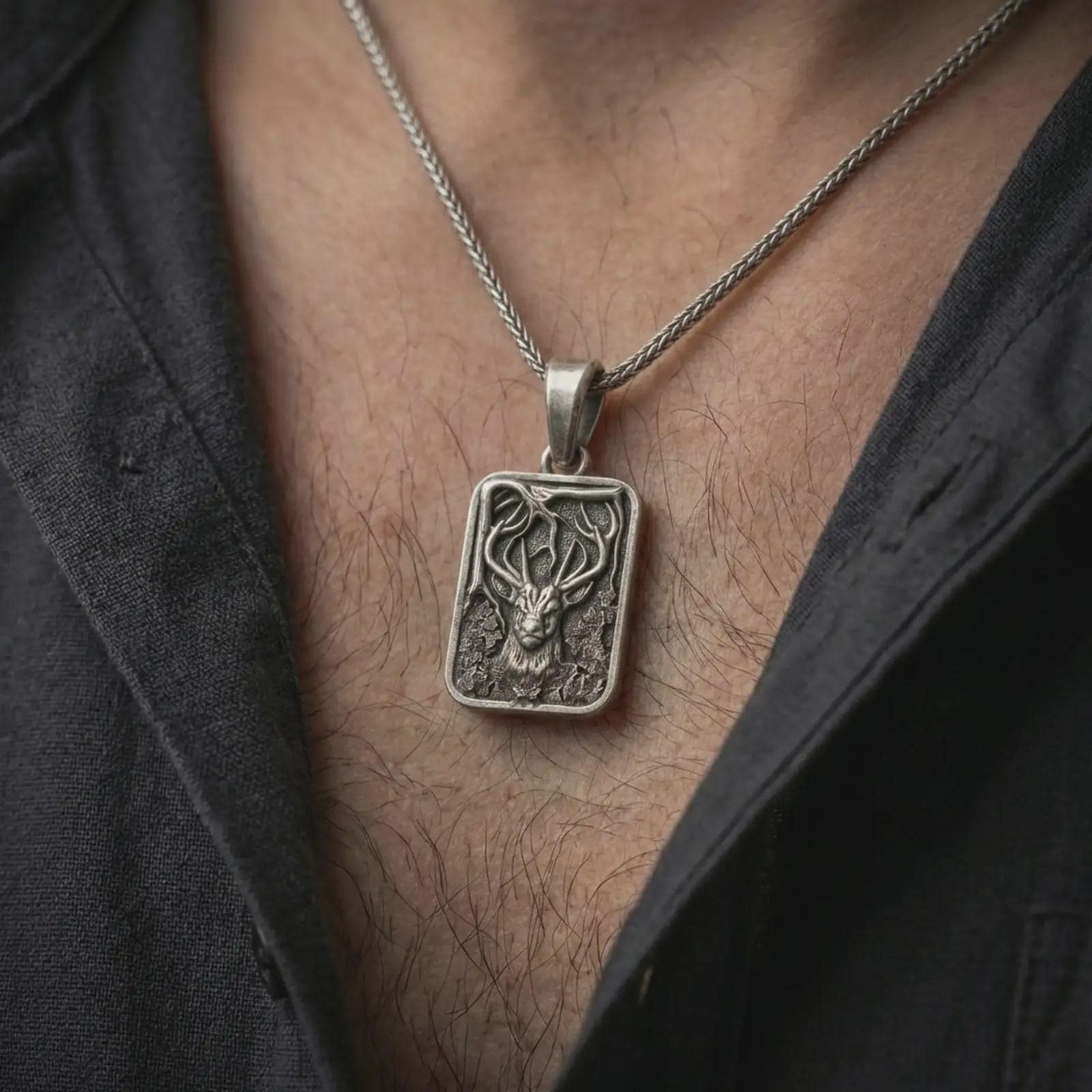 Oxidized stag forest pendant necklace worn on the neck, styled in a dark lifestyle portrait with an open shirt and elegant nature-inspired presentation.