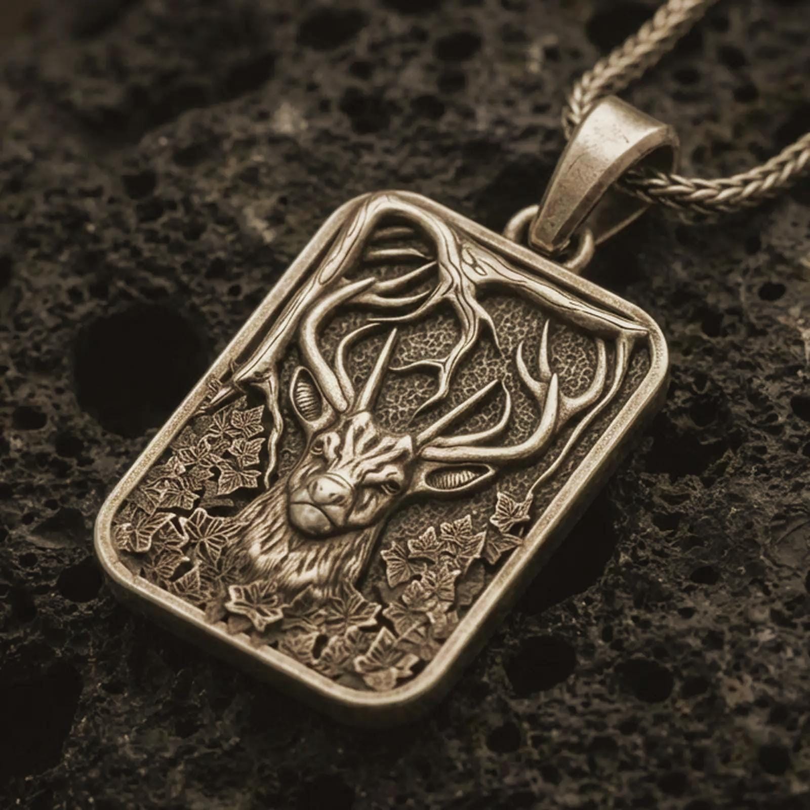 Bronze stag forest pendant necklace with an oxidized finish resting on textured volcanic rock, captured in a close-up premium studio composition.