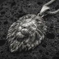 Load image into Gallery viewer, Sterling silver lion head pendant necklace with an oxidized finish resting on textured volcanic rock, captured in a close-up premium studio composition.
