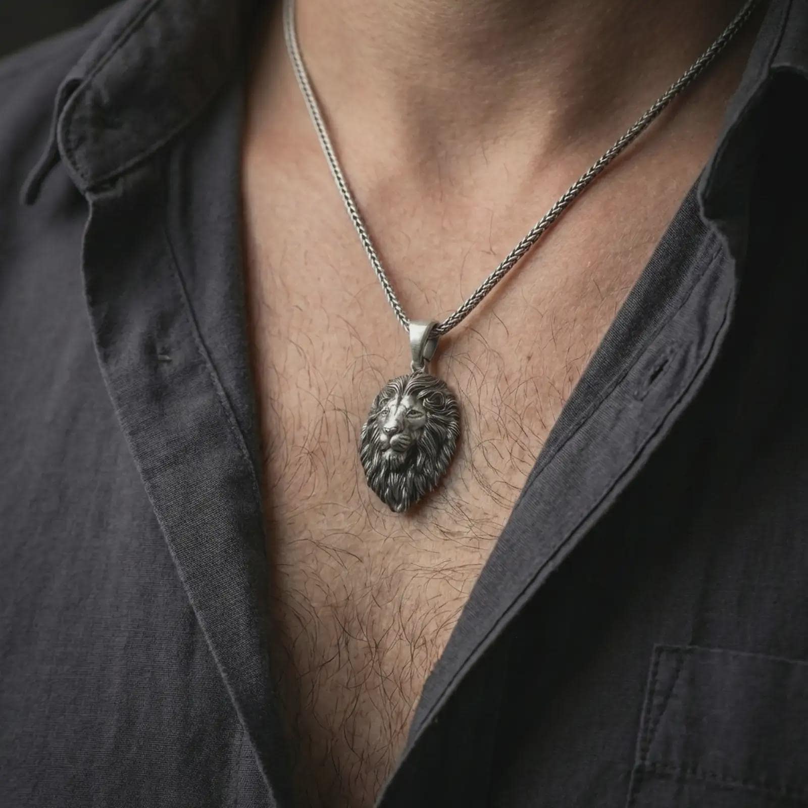 Oxidized lion head pendant necklace worn on the neck, styled in a dark lifestyle portrait with an open shirt and bold masculine presentation.