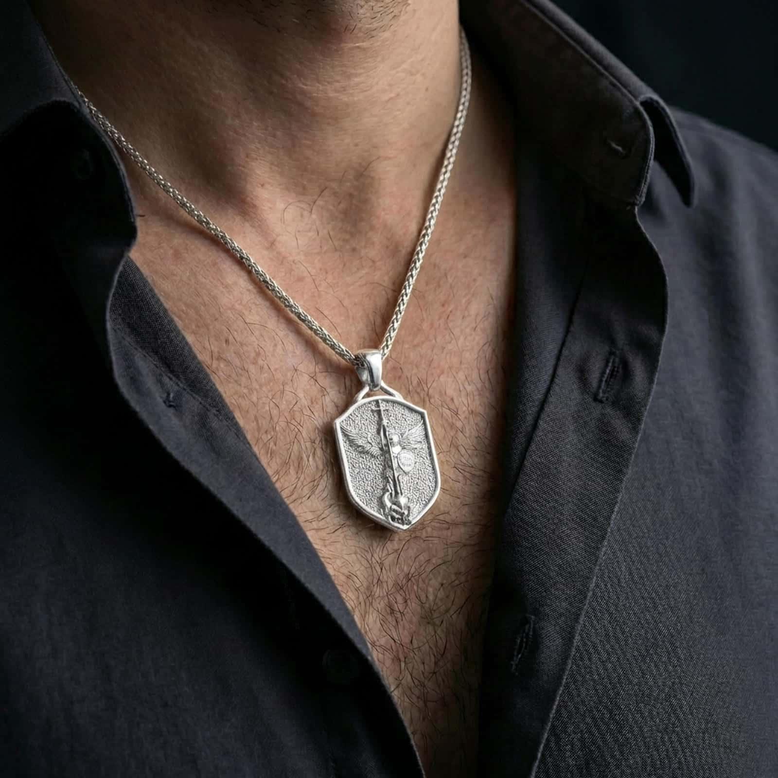 Polished silver Saint Michael shield pendant necklace worn on the neck, shown against the chest in a clean and elegant everyday wear composition.