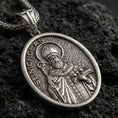 Load image into Gallery viewer, Sterling silver Saint Nicholas pendant necklace with an oxidized finish resting on textured volcanic rock, captured in a close-up premium studio composition.
