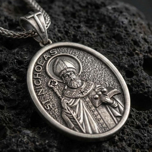 Sterling silver Saint Nicholas pendant necklace with an oxidized finish resting on textured volcanic rock, captured in a close-up premium studio composition.