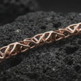 Load image into Gallery viewer, Rose gold plated DNA helix chain necklace on dark volcanic rock, photographed in a detailed premium studio macro view.
