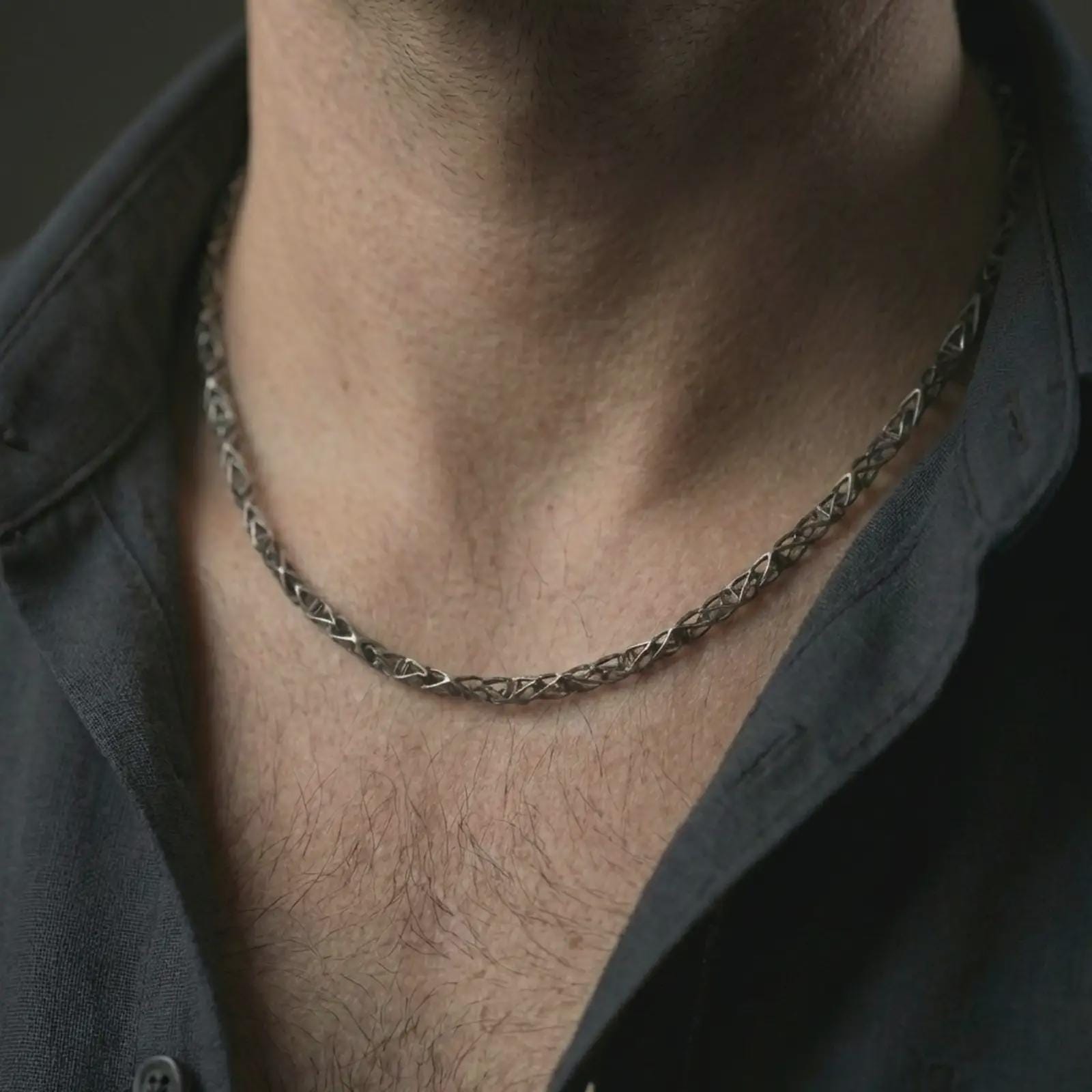 Oxidized DNA helix chain necklace worn on the neck, styled in a dark lifestyle portrait with an open shirt and modern intellectual presentation.