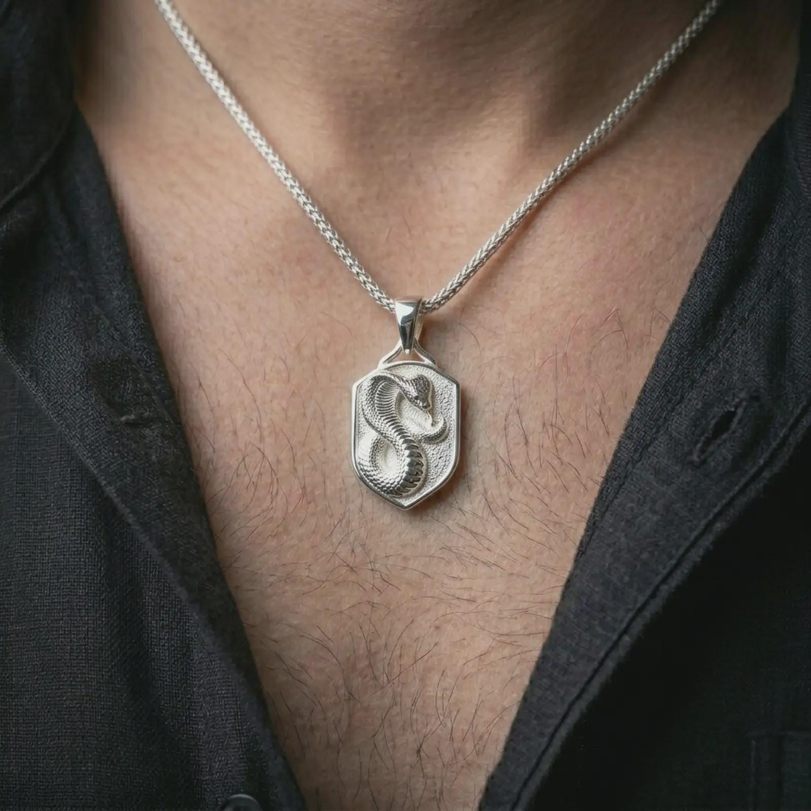 Polished silver cobra shield pendant necklace worn on the neck, shown against the chest in a clean and striking everyday wear composition.