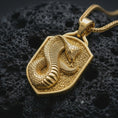 Load image into Gallery viewer, Gold plated cobra shield pendant necklace presented on porous volcanic rock, highlighting the mystical snake guardian motif in a luxurious close-up jewelry image.
