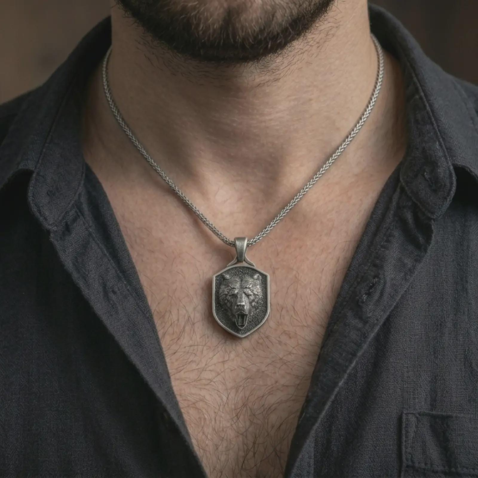 Oxidized roaring bear shield pendant necklace worn on the neck, styled in a dark lifestyle portrait with an open shirt and bold warrior presentation.