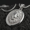 Load image into Gallery viewer, Polished silver lion medallion pendant necklace displayed on black volcanic rock, shown in a refined macro product shot with majestic lion face relief, flowing mane detail, and oval frame.
