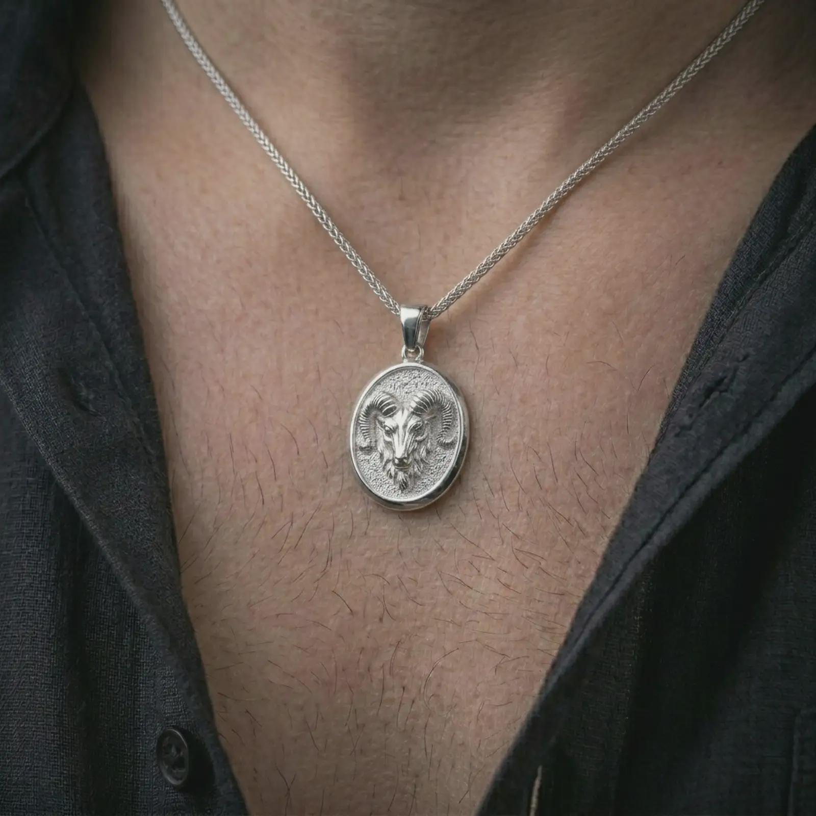 Polished silver ram head pendant necklace worn on the neck, shown against the chest in a clean and striking everyday wear composition.