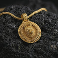Load image into Gallery viewer, Gold plated Fenrir wolf pendant necklace presented on porous volcanic rock, highlighting the mythical wolf motif in a luxurious close-up jewelry image.
