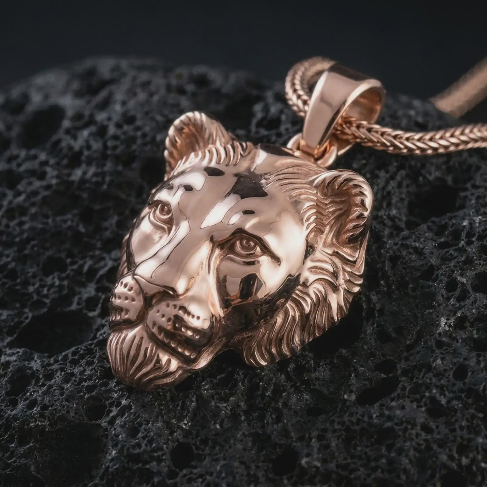 Rose gold plated 3D lioness pendant necklace on dark volcanic rock, photographed in a detailed premium studio macro view.