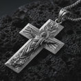 Load image into Gallery viewer, Sterling silver Jesus Ascension cross pendant necklace with an oxidized finish resting on textured volcanic rock, captured in a close-up premium studio composition.
