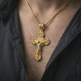 Load image into Gallery viewer, Gold plated Saint Benedict crucifix necklace worn on the neck, captured on a human model in a premium dark-toned lifestyle frame.
