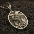 Load image into Gallery viewer, Bronze Jesus carrying cross pendant necklace with an oxidized finish resting on textured volcanic rock, captured in a close-up premium studio composition.
