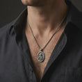 Load image into Gallery viewer, Oxidized Jesus Christ pendant necklace worn on the neck, styled in a dark lifestyle portrait with an open shirt and masculine presentation.
