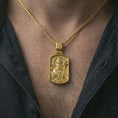 Load image into Gallery viewer, Gold plated Saint Patrick dog tag pendant necklace worn on the neck, captured on a human model in a premium dark-toned lifestyle frame.
