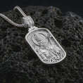 Load image into Gallery viewer, Polished silver Saint Patrick dog tag pendant necklace displayed on black volcanic rock, shown in a refined macro product shot with detailed bishop figure, staff, and engraved border pattern.
