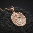 Load image into Gallery viewer, Rose gold plated Saint Michael Archangel pendant necklace on dark volcanic rock, photographed in a detailed premium studio macro view.
