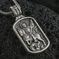 Load image into Gallery viewer, Sterling silver Saint George dog tag pendant necklace with an oxidized finish resting on textured volcanic rock, captured in a close-up premium studio composition.

