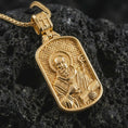 Load image into Gallery viewer, Gold plated Saint Benedict dog tag pendant necklace presented on porous volcanic rock, highlighting the rectangular devotional form in a luxurious close-up jewelry image.

