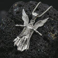 Load image into Gallery viewer, Polished silver Archangel Michael pendant necklace displayed on black volcanic rock, shown in a refined macro product shot with detailed winged figure and sculpted armor relief.
