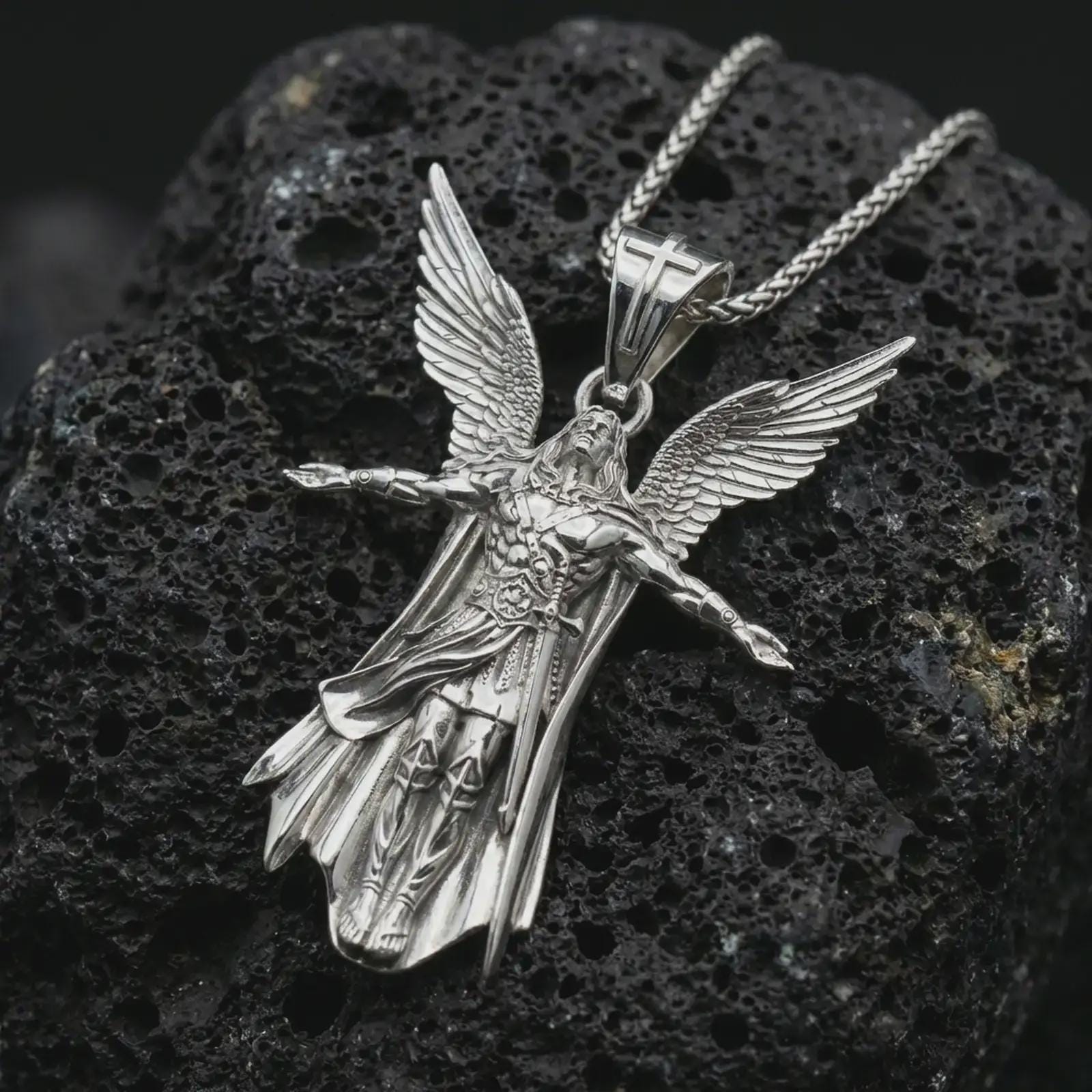 Polished silver Archangel Michael pendant necklace displayed on black volcanic rock, shown in a refined macro product shot with detailed winged figure and sculpted armor relief.
