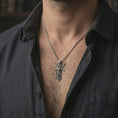 Load image into Gallery viewer, Oxidized Archangel Michael pendant necklace worn on the neck, styled in a dark lifestyle portrait with an open shirt and masculine presentation.
