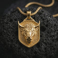 Load image into Gallery viewer, Gold plated bull head shield pendant necklace presented on porous volcanic rock, highlighting the Taurus-inspired power motif in a luxurious close-up jewelry image.

