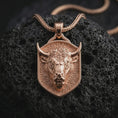 Load image into Gallery viewer, Rose gold plated bull head shield pendant necklace on dark volcanic rock, photographed in a detailed premium studio macro view.
